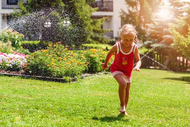 A girl plays on a healthy lawn made possible by Yard Master Services.