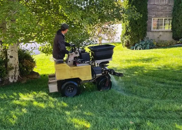 A lawn care technician applies fertilizer with a riding machine.