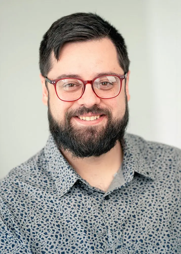 A portrait photo of a project manager at Yard Master Services. He is smiling, wearing glasses, has a beard, and is wearing a patterned shirt.